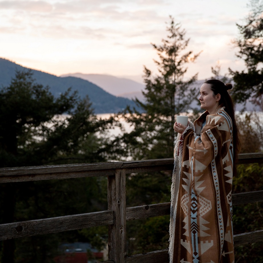 Woman wrapped in a blanket drinking tea on a terrace