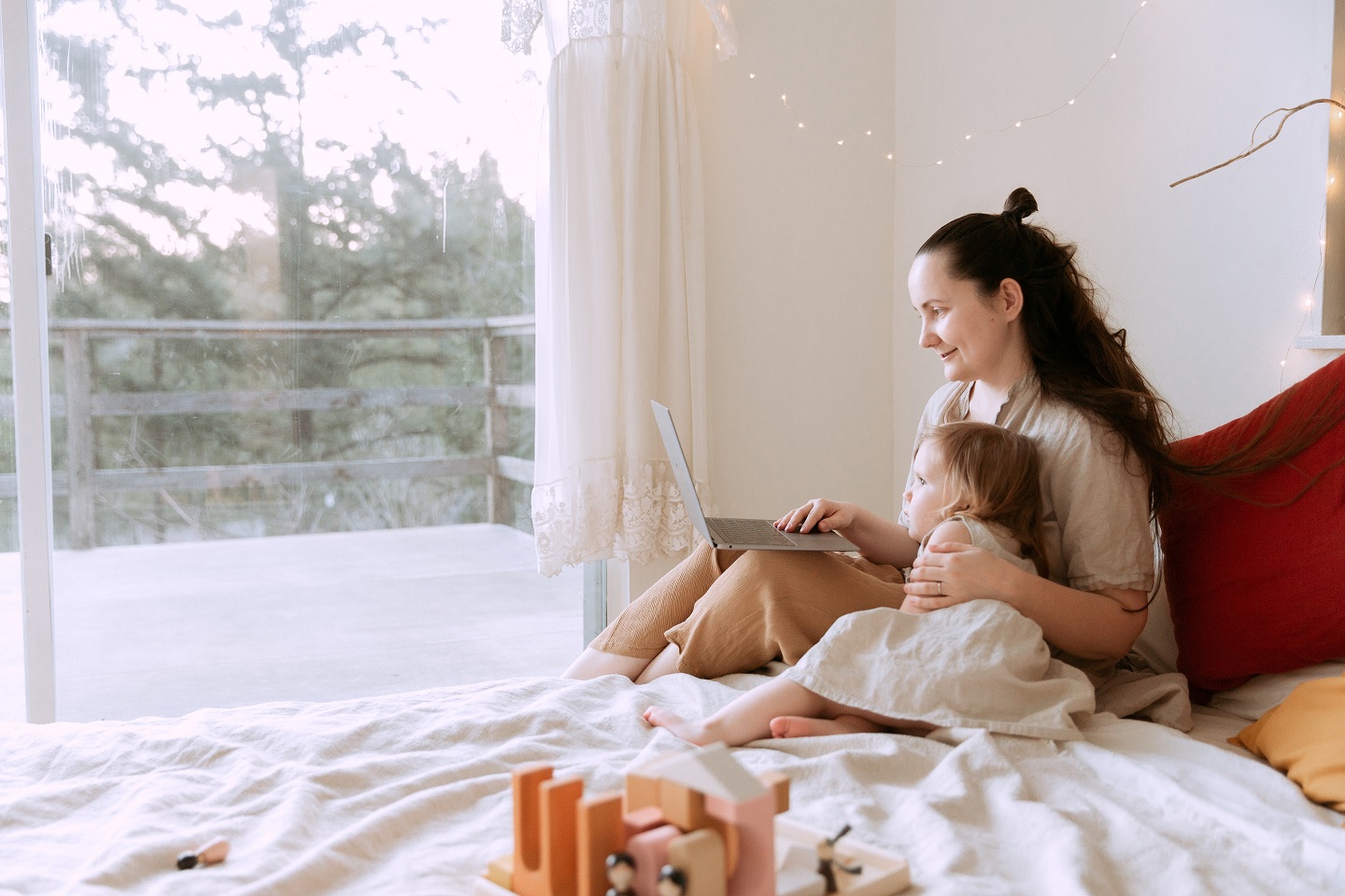 Mother and child sitting on bed and with an open laptop